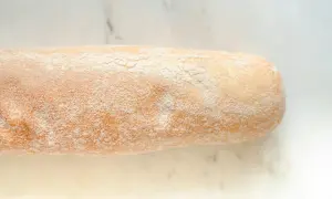 Chleb rustykalny, lekko oprószony mąką, z chrupiącą skórką, gotowy do krojenia.