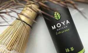 Tradycyjny bambusowy chasen obok puszki MOYA Matcha Codzienna. Idealne narzędzia, by poznać, co to matcha.