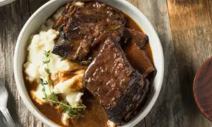 Pyszne żeberka w sosie własnym z puree ziemniaczanym, udekorowane gałązką tymianku. Idealne na obiad.
