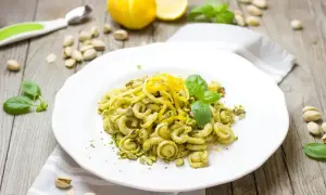 Makaron z pesto ze słoika, posypany pistacjami i skórką cytrynową, ozdobiony listkami bazylii.