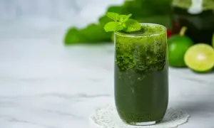Orzeźwiający koktajl z jarmużu, ozdobiony listkami mięty, z limonkami w tle. Idealny na zdrowy początek dnia.