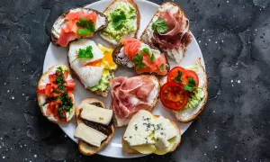 Talerz pełen pysznych sznytek: z łososiem, awokado, jajkiem w koszulce, szynką parmeńską, pomidorami i serami.