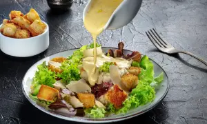 Polewany sosem sos sałatka cezar oryginalny przepis, z chrupiącymi grzankami i parmezanem.