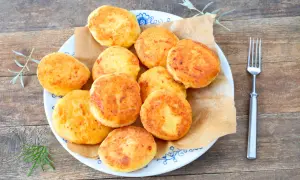 Talerz pełen złotych, puszystych arepas, ułożonych na brązowym papierze. Obok widelec i gałązki ziół.