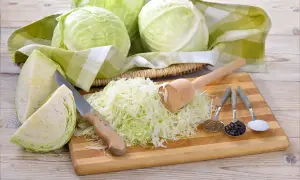 Kapusta, nóż, tłuczek i przyprawy: kmin rzymski, pieprz, sól. Idealne składniki, by dowiedzieć się, ile soli do kiszenia kapusty.