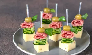 Koreczki na przyjęcie: ser, salami, ogórek, oliwka i listek ziół na wykałaczce.