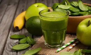 Zielony koktajl owocowy z jabłkiem, bananem i awokado, obok świeżego szpinaku.