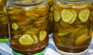 Słoiki pełne plasterków ogórków w zalewie z curry, ze skórką, gotowe do spożycia.