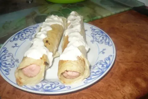 Dwa parówki w cieście naleśnikowym, polane sosem. Pyszna przekąska na szybko.