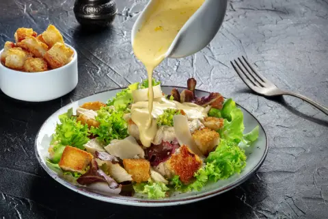 Polewany sosem sos sałatka cezar oryginalny przepis, z chrupiącymi grzankami i parmezanem.