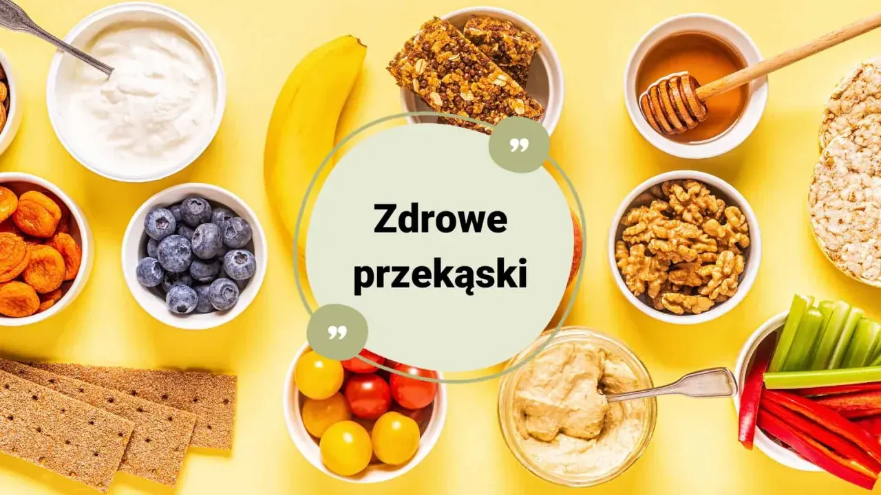 Zestawienie zdrowych przekąsek: jogurt, jagody, suszone morele, banan, batoniki musli, miód, orzechy, krakersy, pomidorki, hummus, papryka i seler.
