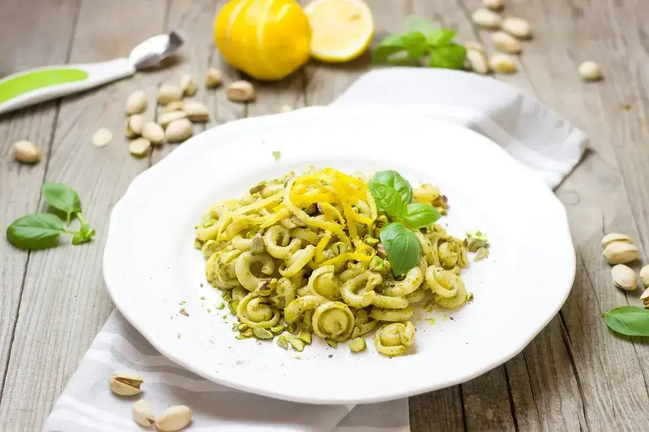 Makaron z pesto ze słoika, posypany pistacjami i skórką cytrynową, ozdobiony listkami bazylii.