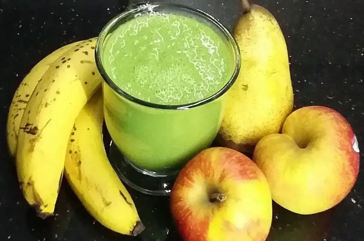 Zielony koktajl ze szpinakiem, banany, gruszka i jabłka na czarnym tle. Pyszny i zdrowy napój.
