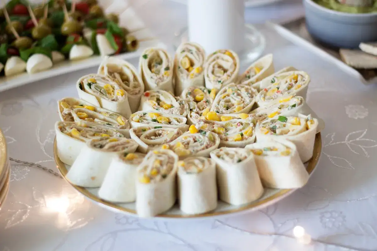 Talerz pełen pysznych roladek z tortilli, idealnych jako finger food. Wypełnione kremowym farszem z kukurydzą i warzywami, kuszą smakiem.
